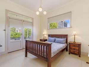 a bedroom with a bed and two windows at Fairholme Townhouse in Warrnambool
