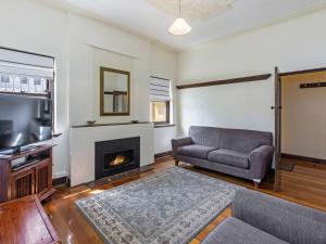 a living room with a couch and a fireplace at Fairholme Apartment in Warrnambool
