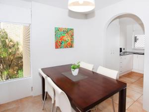 a dining room with a wooden table and white chairs at Headlands 10 Two Bedroom Beachside Apartment with Magical Ocean Views Great Value for Money in Alexandra Headland