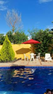 een tafel en stoelen en een parasol naast een zwembad bij CASA QUINTA VILLA ESPERANZA in Guayabal