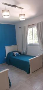a blue bedroom with a bed and a window at Complejo Los Plumerillos in Chascomús