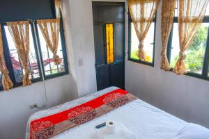 um quarto com uma cama com um cobertor vermelho e janelas em Hotel Villa del Lago em San Pedro La Laguna