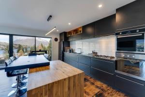 a kitchen with black cabinets and a large window at Viscount Haven - Lake Views in Queenstown