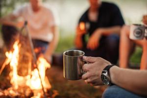a person holding a coffee mug in front of a fire at Muroran Gramping - Golf Resort in Muroran