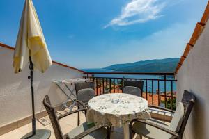 a table and chairs on a balcony with an umbrella at Apartments Josip in Rabac