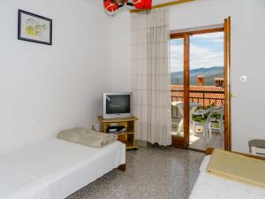a room with two beds and a tv and a balcony at Apartments Josip in Rabac