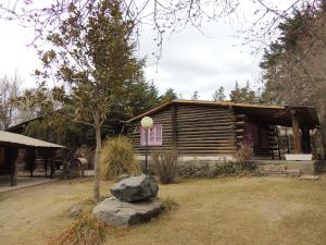 a log cabin with a tree and a rock at Cabañas San Francisco in Potrerillos