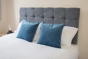 a bed with blue and white pillows on it at Luke Stays - Finsbury Street in Monkwearmouth