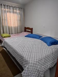a bed with a black and white comforter and a window at Sítio Paraíso Central - Casinha in Rodeio