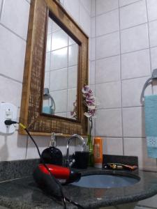 um lavatório de casa de banho com espelho e uma scooter vermelha em Estiloso 2 Quartos Wifi e SmarTV em Guarapari