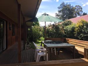 a table and chairs with an umbrella on a deck at Chris's Cabin in Greytown