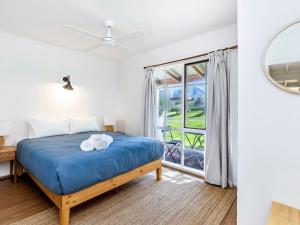 - une chambre avec un lit bleu et une fenêtre dans l'établissement Beach Break, à Port Fairy