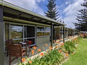 Casa con terraza con mesa y sillas en Cascade Garden Apartments, en Burnt Pine