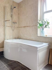 a white bath tub in a bathroom with a window at Riverside Lodge - Quaint Victorian Home By The River in York