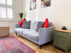 a living room with a gray couch with red pillows at Riverside Lodge - Quaint Victorian Home By The River in York