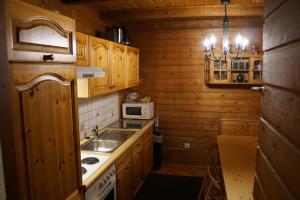 cocina con armarios de madera, fregadero y microondas en Gerlitzen-Hütte, en Treffen