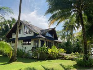 a house with palm trees in front of it at Sandy Feet Siargao in General Luna
