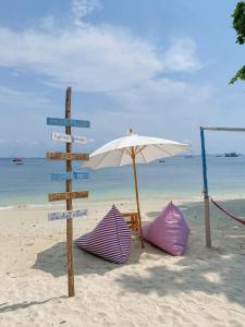 een straatbord op het strand met twee tenten en een parasol bij Minnie Seaview Resort in Ko Samed