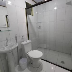 a white bathroom with a toilet and a sink at Pousada São Miguel in Cunha