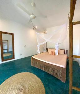 um quarto com uma cama, uma ventoinha de tecto e um espelho. em Siri Beach Lodge em Nungwi