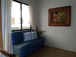 大雅台的住宿－Pine Suites Tagaytay 2BR Penthouse with Netflix and FREE parking，一张蓝色沙发,坐在一个窗户的房间
