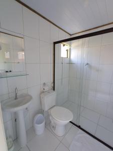 a white bathroom with a toilet and a sink at Pousada São Miguel in Cunha