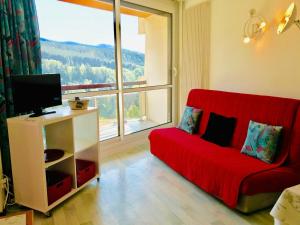 a living room with a red couch and a large window at Appartement Villard-de-Lans, 2 pièces, 6 personnes - FR-1-515-21 in Villard-de-Lans