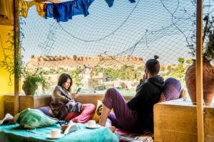 een groep mensen die op de grond zitten en uit een raam kijken bij The Hosteller Jaisalmer in Jaisalmer