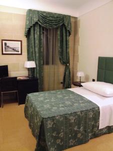シラクーサにあるドムス マリアエ ベネッセーレのベッドルーム1室(ベッド1台、デスク、窓付)