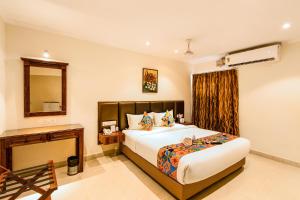 1 dormitorio con cama, mesa y espejo en FabHotel Blossoms Service Apartment en Chennai