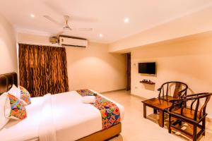 a room with a bed, chair, table and television at FabHotel Blossoms Service Apartment in Chennai