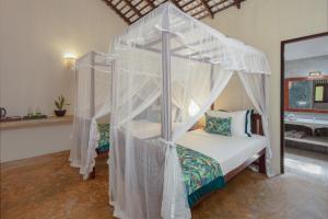 a bedroom with a canopy bed with white curtains at Green Escape Unawatuna in Unawatuna