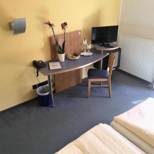 a room with a desk with a computer and a chair at Hotel Ambiente in Halberstadt