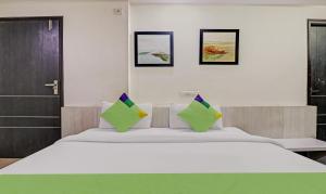 a bedroom with a large white bed with green pillows at Treebo Trend Mohit Regency in Bhopal