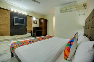 1 dormitorio con 1 cama blanca grande y TV en FabHotel Staywell en Gurgaon