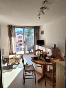 a living room with a table and chairs and a large window at STUDIO pied des pistes et commerces in Les Deux Alpes
