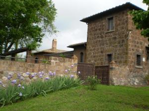 ein Haus mit einem Steinzaun und lila Blumen in der Unterkunft Casale di Befania in Vetralla
