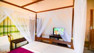a bedroom with a canopy bed and a television at Villa Yehinsa - Galle Fort in Galle