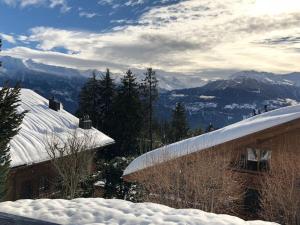 a snow covered roof of a building with mountains in the background at Appartement 3 pièces avec magnifique vue in Crans-Montana