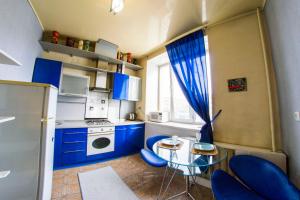 オムスクにあるRENT-сервис Apartment on Maslennikova 9の小さなキッチン(青いキャビネット、ガラスのテーブル付)