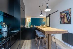 ビアリッツにあるCOCOON KEYWEEK Holiday House with lovely patio in Biarritz city centerのキッチン(黒いキャビネット、木製テーブル付)