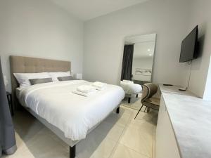 a bedroom with a large white bed and a television at ShineAppart Marmande Centre in Marmande