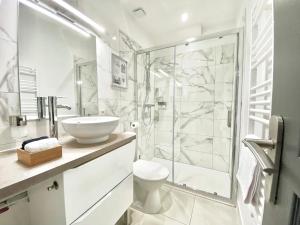 La salle de bains blanche est pourvue d'une douche et d'un lavabo. dans l'établissement ShineAppart Marmande Centre, à Marmande