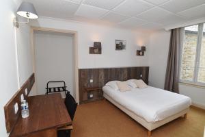 a bedroom with a bed and a desk and a window at Logis Hôtel du Commerce in Quintin