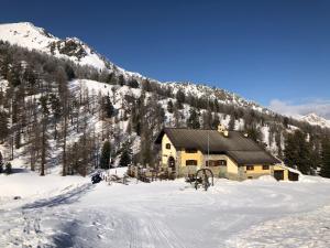 una baita di tronchi nella neve con una montagna di Rifugio Baita Gimont a Cesana Torinese