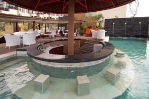 una piscina con mesa, sillas y sombrilla en ABISHA Resort Jimbaran, en Jimbaran