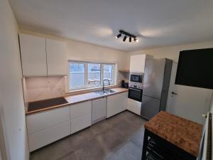  La cuisine est équipée de placards blancs et d'un réfrigérateur. dans l'établissement Duplex Appartement Opex, à Ostende