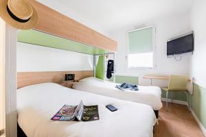 une chambre d'hôtel avec deux lits et une télévision à écran plat dans l'établissement ibis budget Carcassonne Aéroport - A61, à Carcassonne
