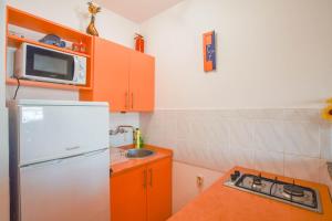 kuchnia z pomarańczowymi szafkami i białą lodówką w obiekcie Apartments Clair w mieście Pag