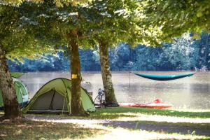 a group of tents and a boat on a lake at Camping Le château du gibanel in Saint-Martial-Entraygues